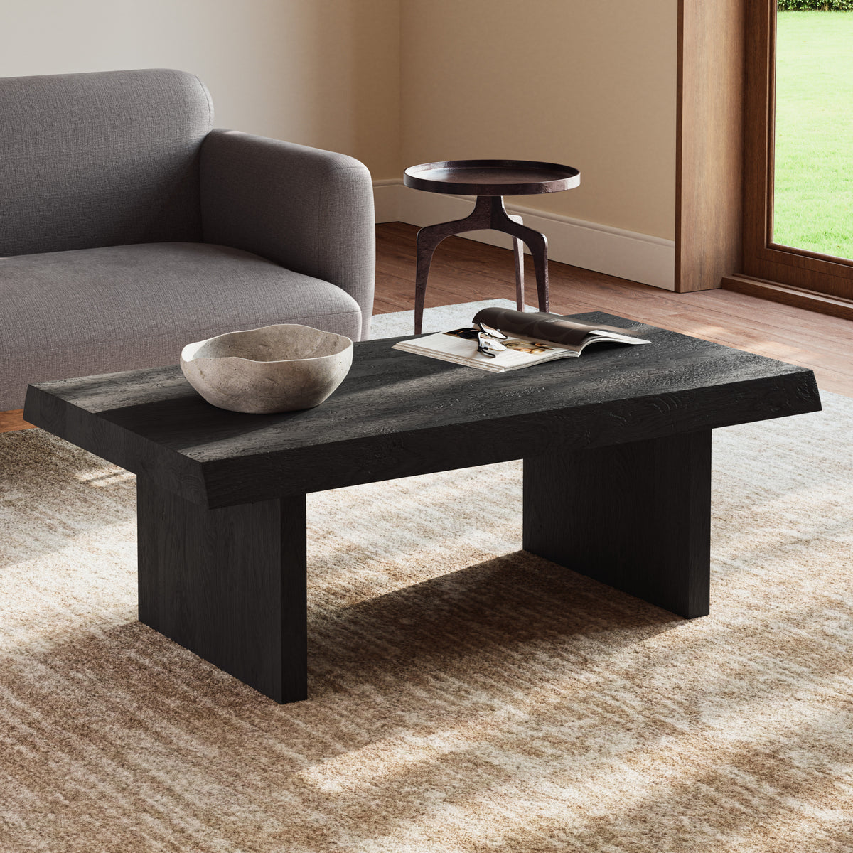 Brooks Coffee Table by Urbia — dark solid acacia table beside a sofa, three-quarter view