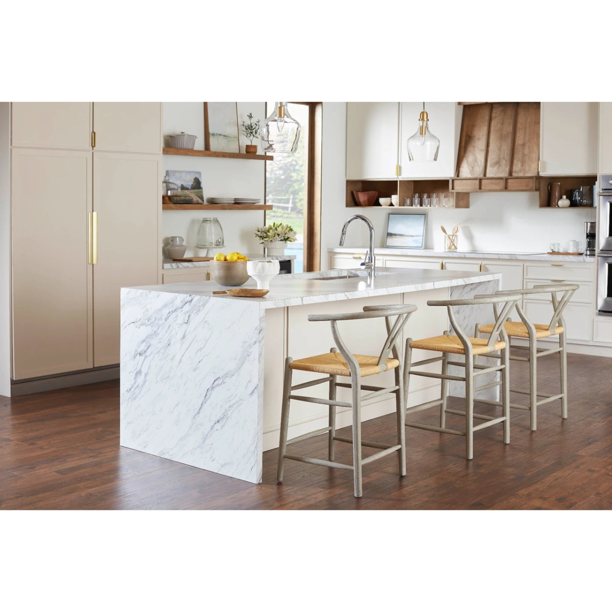 Three Oslo Counter Stools by Villa & House with gray-finished oak frames and woven rope seats around a marble kitchen island.