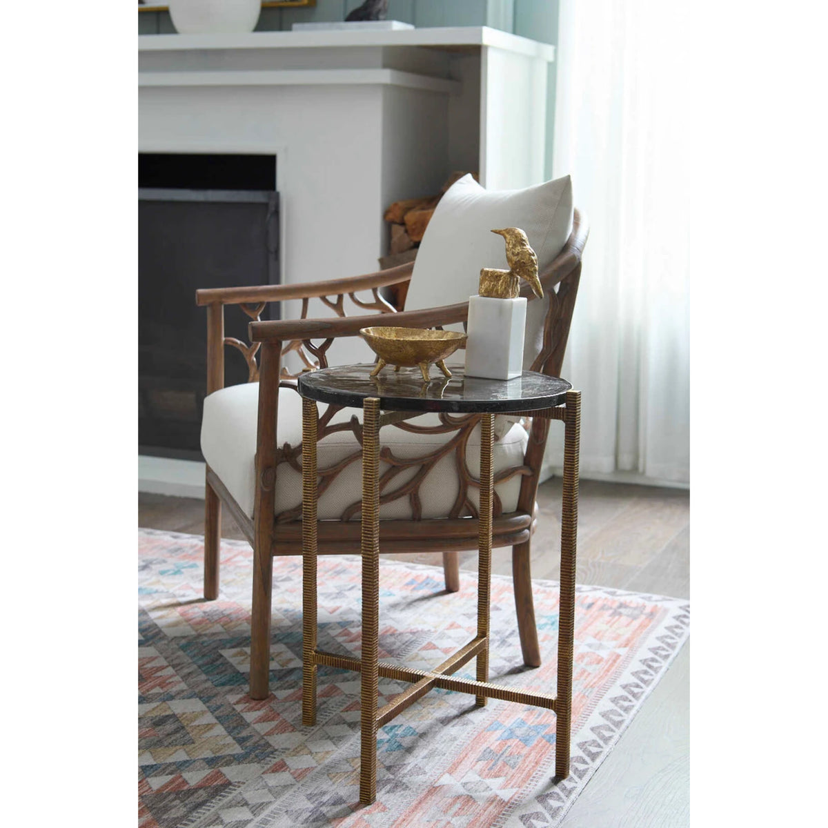 Gideon Accent Table by Villa & House — antique brass-textured three-leg table beside a lounge chair in a living room
