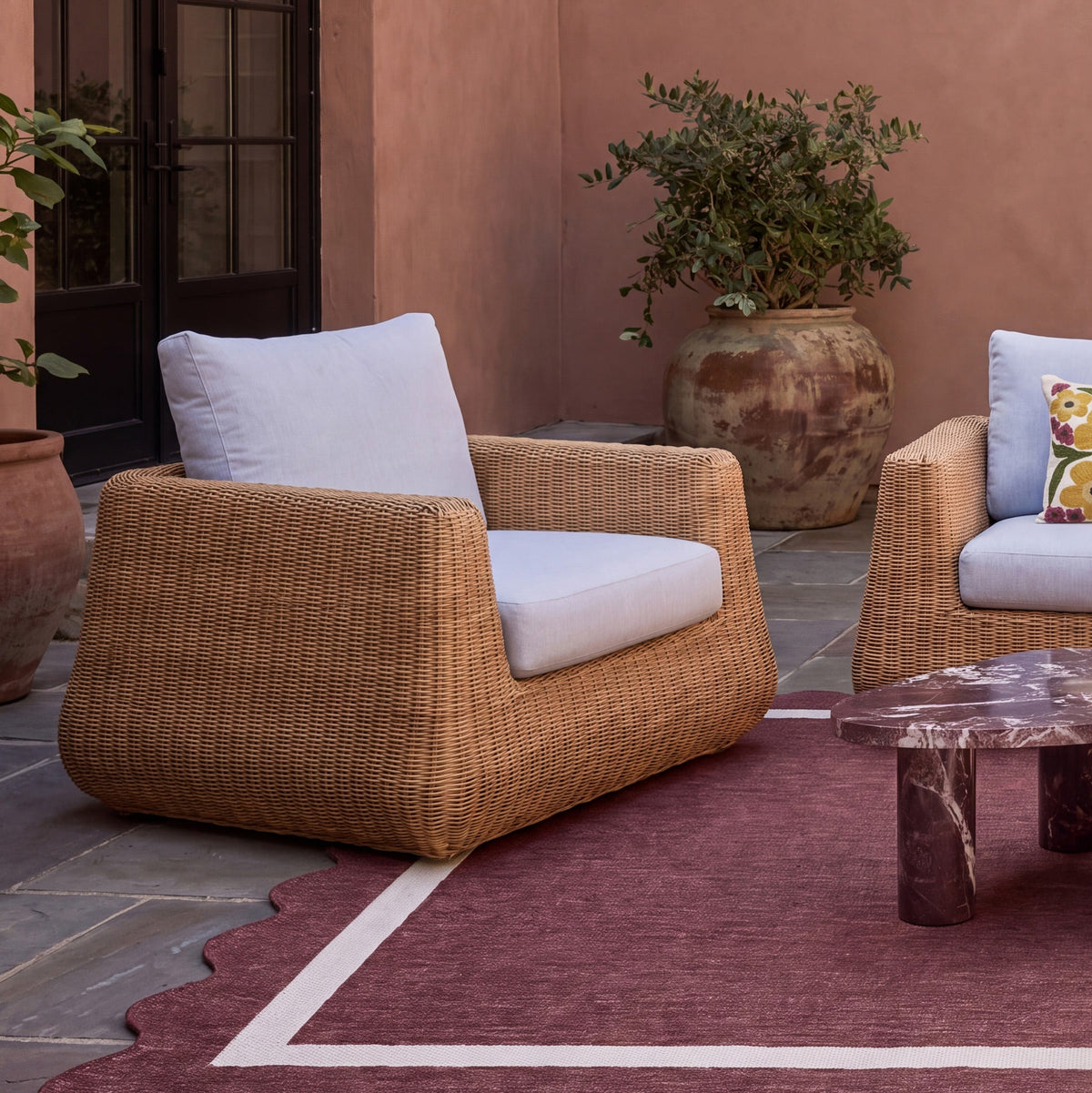 Dana Outdoor Accent Chair by TOV Furniture — cream cushions and resin wicker in a patio setting, rear angled view
